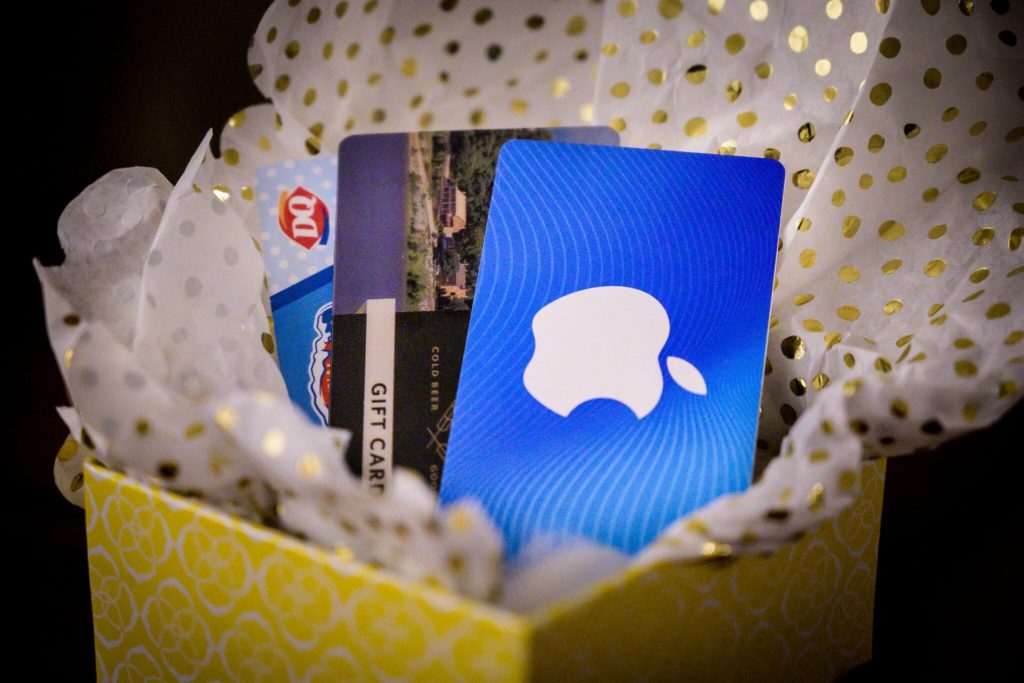 Yellow box with gift cards inside to Apple, Dairy Queen, and another place. White and gold poka dot tissue paper is nested in the box for decorations.