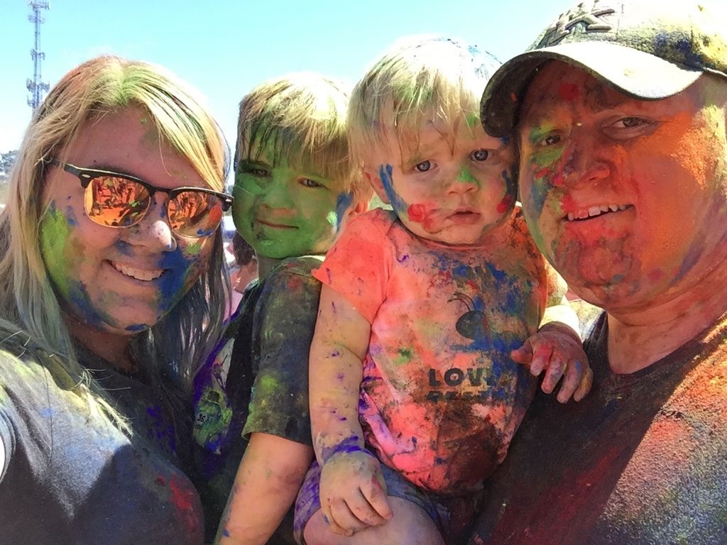 Happy family with two young boys at the Color Run. It is at the end of the race becuase you can see the entire family is covered in colorful powder.