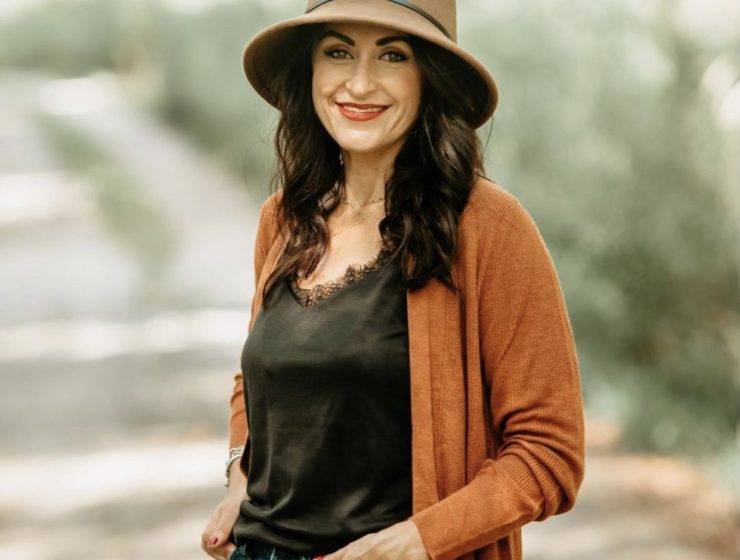 Women in brown cami with orange sweater and tan wool hat.