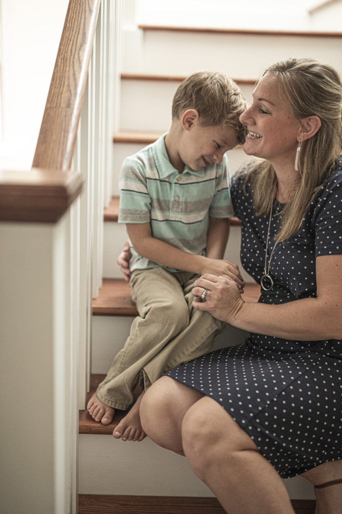 mom and autistic son on stairs laughing