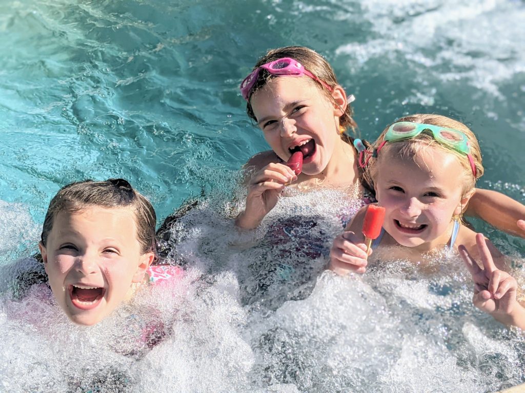 Little girls eating popsicles in a hot tube.