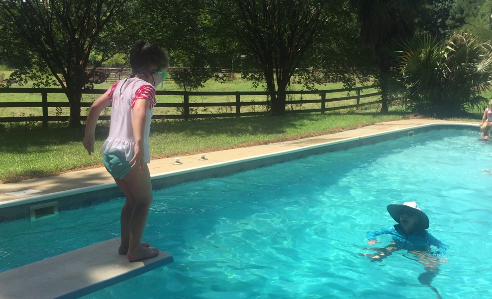 little girl jumping off diving board at swimming lessons